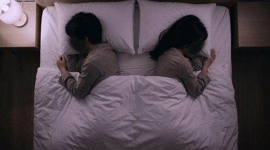Couple endormi dans un lit double vu du dessus, separes par un espace vide